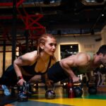 a man and a woman doing push-up challenge with dumbbells