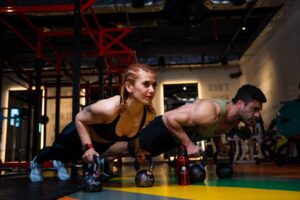 a man and a woman doing push-up challenge with dumbbells