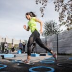 woman in green tank top and black leggings doing outdoor exercises to reduce stress