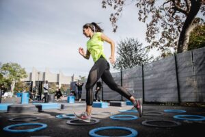 woman in green tank top and black leggings doing outdoor exercises to reduce stress