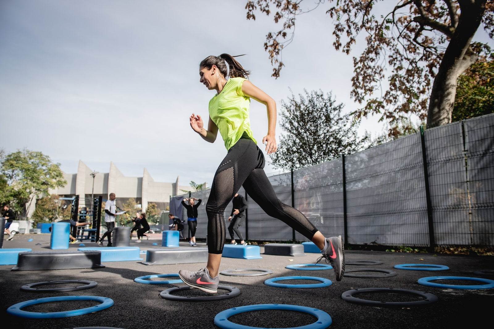woman in green tank top and black leggings doing outdoor exercises to reduce stress